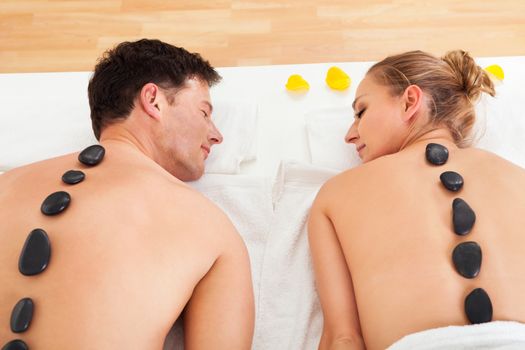 Couple enjoying a hot stone massage in a spa where heated stones are placed along the spine to relax the muscles