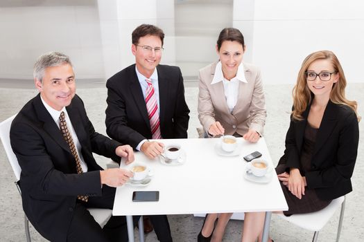 Business executives sitting around a table enjoying a relaxing cup of coffee together during a break