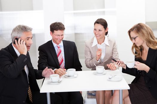 Business executives sitting around a table enjoying a relaxing cup of coffee together during a break