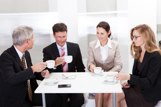 Business colleagues relaxing over coffee or having an impromptu meeting in the cafeteria