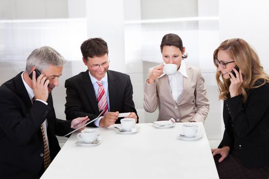 Business executives sitting around a table enjoying a relaxing cup of coffee together during a break