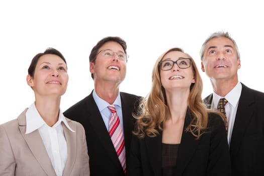 Four happy diverse professional business partners standing in a row looking upwards with a smile isolated on white