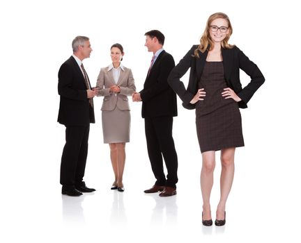 Successful attractive businesswoman standing with her hands on her hips with her team of two business men and a woman standing