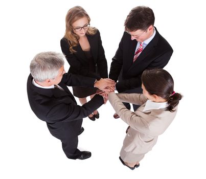 Group of four diverse businesspeople standing in a circle facing each other holding hands in a team