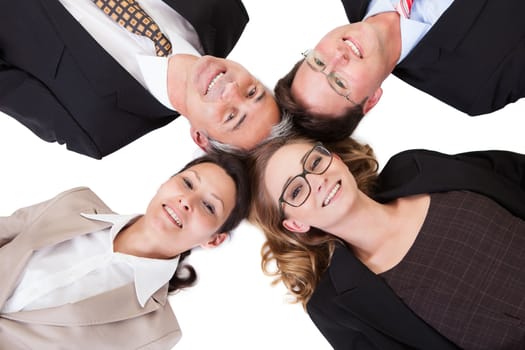 Conceptual image of four businesspeople with their heads together looking directly down at the camera isolated on white
