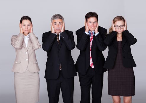 Four diverse businesspeople standing in a row holding their ears in a conceptual representation of the saying - Hear no evil