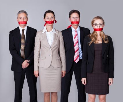 Businesspeople bound by red tape around their mouths standing in a row unable to speak or divulge information