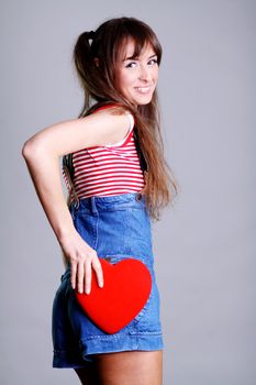 Portrait of a charming young girl on a white background holding a heart