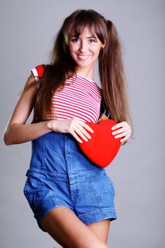 Portrait of a charming young girl on a white background holding a heart
