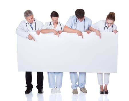 Four attractive professional diverse medical staff holding up a long horizontal blank white banner for your text or advertisement