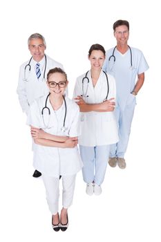 Row of smiling diverse medical doctors and nurses in white uniforms with stethoscopes standing in an oblique receding row isolated on white