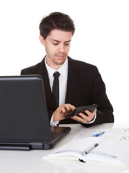 Smiling good looking young accountant sitting at his desk making calculations on a handheld calculator