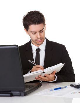 Handsome young businessman concentrating on making a note in his diary or scheduling an appointment or meeting