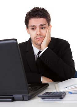 Businessman with a look of hopelessness staring at the screen of his laptop with his head resting in his hands