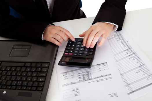 High angle cropped view of the hands of a male accountant doing calculations on a manual calculator while analyzing a report