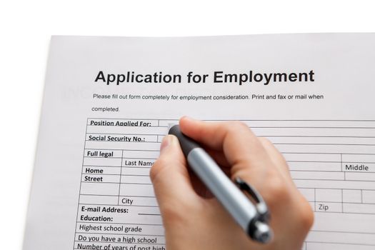 Closeup of a male hand holding a pen completing a job application form in a career and employment concept