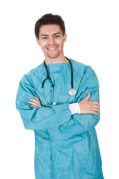 Smiling confident young surgeon wearing a gown and stethoscope standing with his arms crossed isolated on white