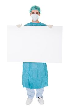 Young male surgeon in a cap and mask holding up a blank banner with copyspace for your text