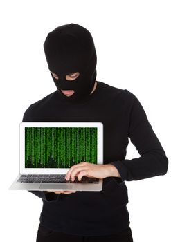 Hacker dressed in black with a mask standing stealing data from a laptop with the screen pointed towards the camera in a breach of security