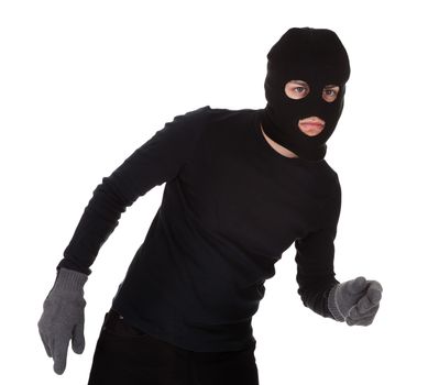 Thief wearing a balaclava dressed in blacked moving stealthily. Isolated on white