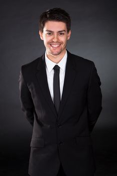 Portrait of smiling businessman over black background