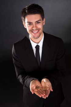 Smiling young businessman holding up a golden key in his hand