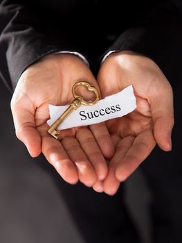 Businessman holding up a golden key in his hand