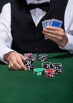 Male poker player about to place a bet moving a stack of tokens towards the centre of the gaming table with his free hand