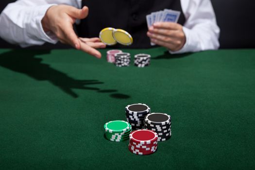 Poker player increasing his stakes throwing tokens onto the gaming table to meet or beat his opponents wager to stay in the game