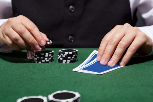 Close-up of a hand of poker player with cards and chips