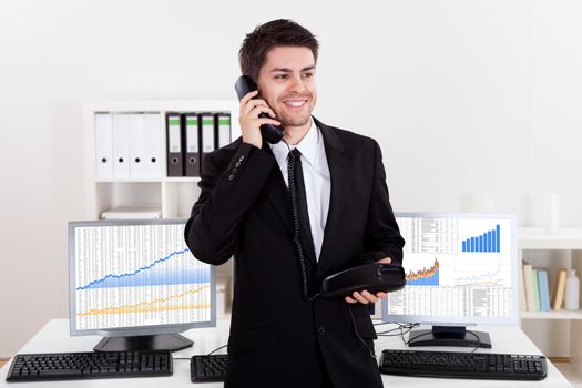 Enthusiastic young male stock broker in a bull market holding a telephone