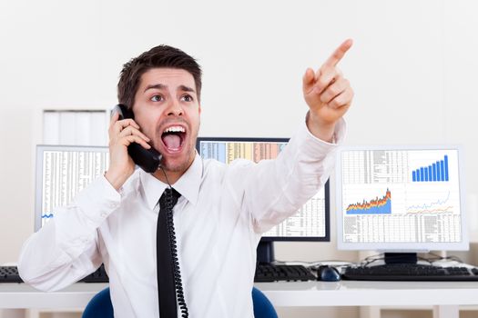Enthusiastic young male stock broker in a bull market holding a telephone and yelling out a buy or sell order on stocks or bonds