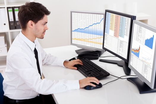 Over the shoulder view of the computer screens of a stock broker trading in a bull market showing ascending graphs
