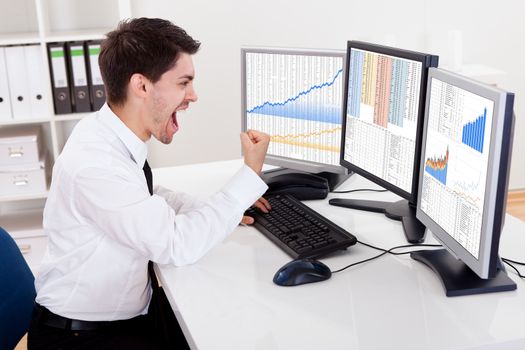 Over the shoulder view of the computer screens of a stock broker trading in a bull market showing ascending graphs