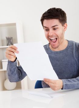 Exultant young man cheering at good news he has just received in a document that he is reading