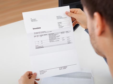 Overhead view of young man reading a invoice document