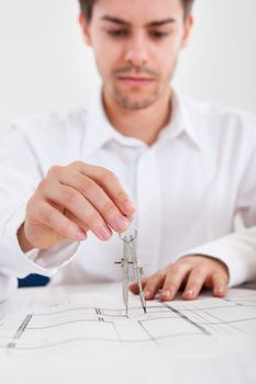 Closeup cropped image of a young male architect working on blueprints spread out on a table