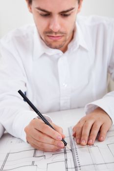 Closeup cropped image of a young male architect working on blueprints spread out on a table