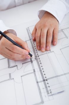 Closeup cropped image of a young male architect working on blueprints spread out on a table
