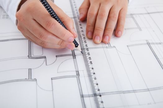 Closeup cropped image of a young male architect working on blueprints spread out on a table