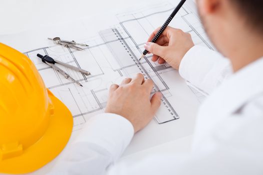 Closeup cropped image of a young male architect working on blueprints spread out on a table