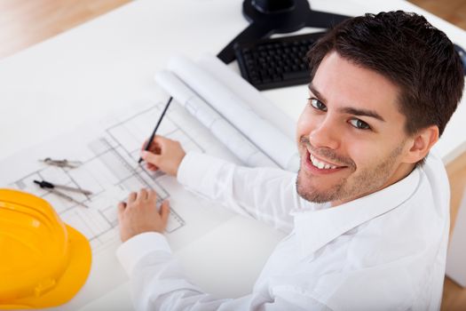 Closeup cropped image of a young male architect working on blueprints spread out on a table