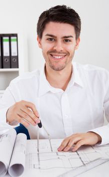 Closeup cropped image of a young male architect working on blueprints spread out on a table