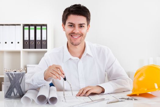 Closeup cropped image of a young male architect working on blueprints spread out on a table