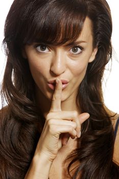 Woman holding her finger over her lips expressing quiet.