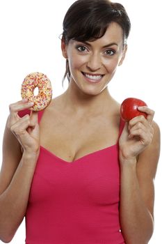 Young woman deciding between an apple or doughnut.