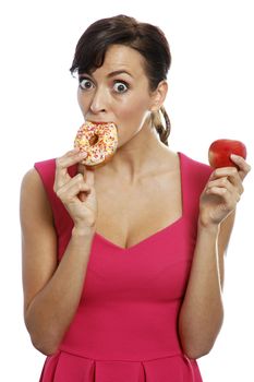 Young woman deciding between an apple or doughnut.