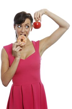 Young woman deciding between an apple or doughnut.