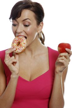 Young woman deciding between an apple or doughnut.