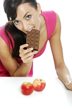 Young woman torn between a chocolate bar and fresh apple